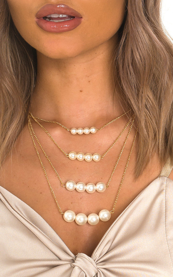 Close-up of a woman wearing the Multi Pearl Drop Design Necklace, featuring a gold chain and pearl drops, highlighting its elegant fashion accessory appeal.