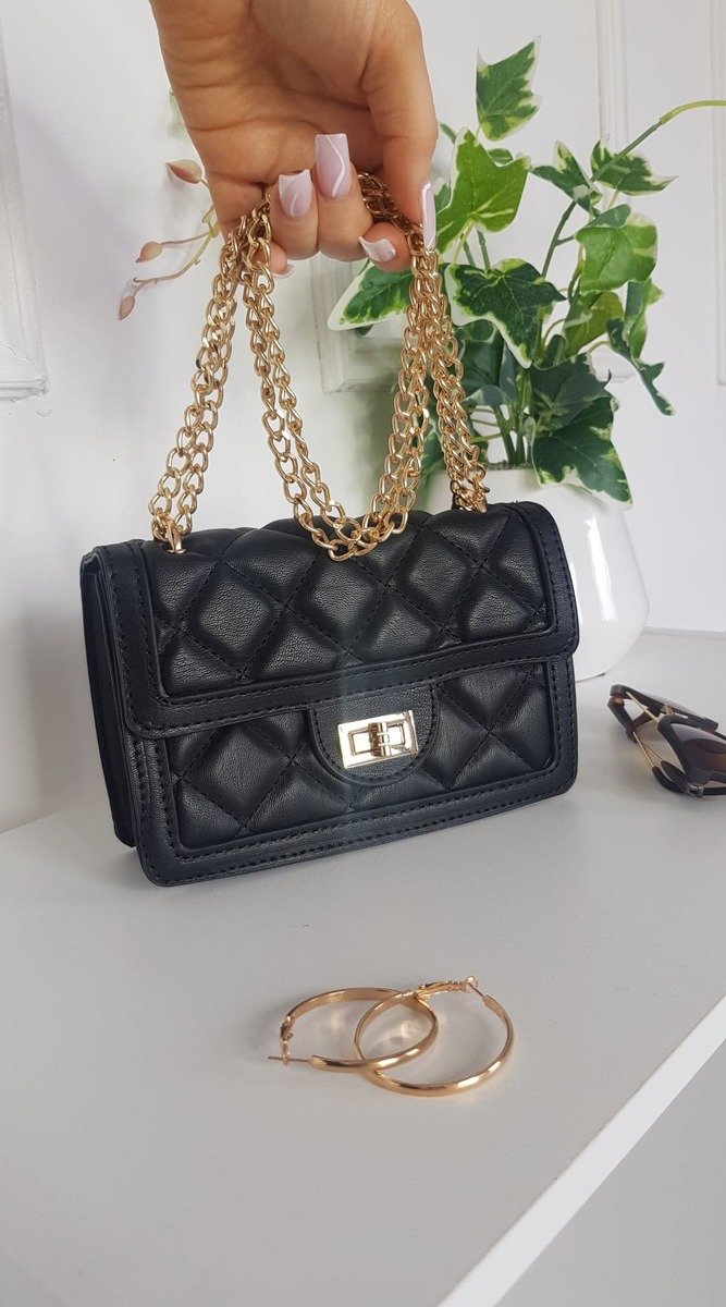 Quilted Chain Detail Handbag with gold chains and fastenings displayed on a shelf, paired with sunglasses, showcasing elegant design for versatile styling.