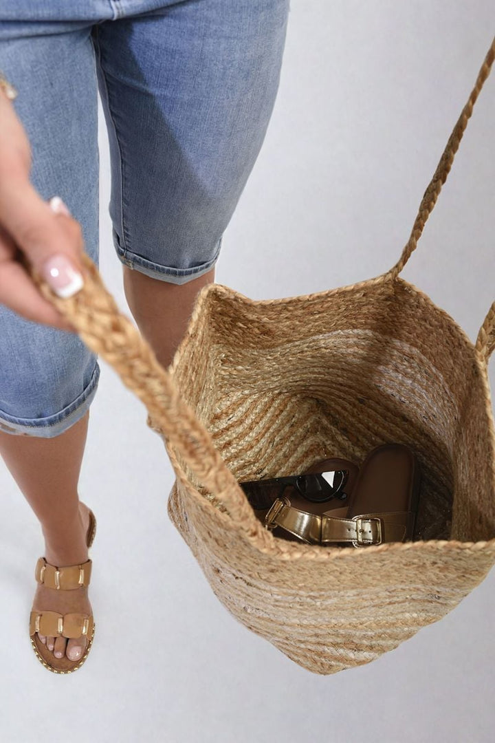 Person holding Striped Beach Braided Tote Bag with shoes inside, showcasing its spacious design and braided handles for stylish functionality.