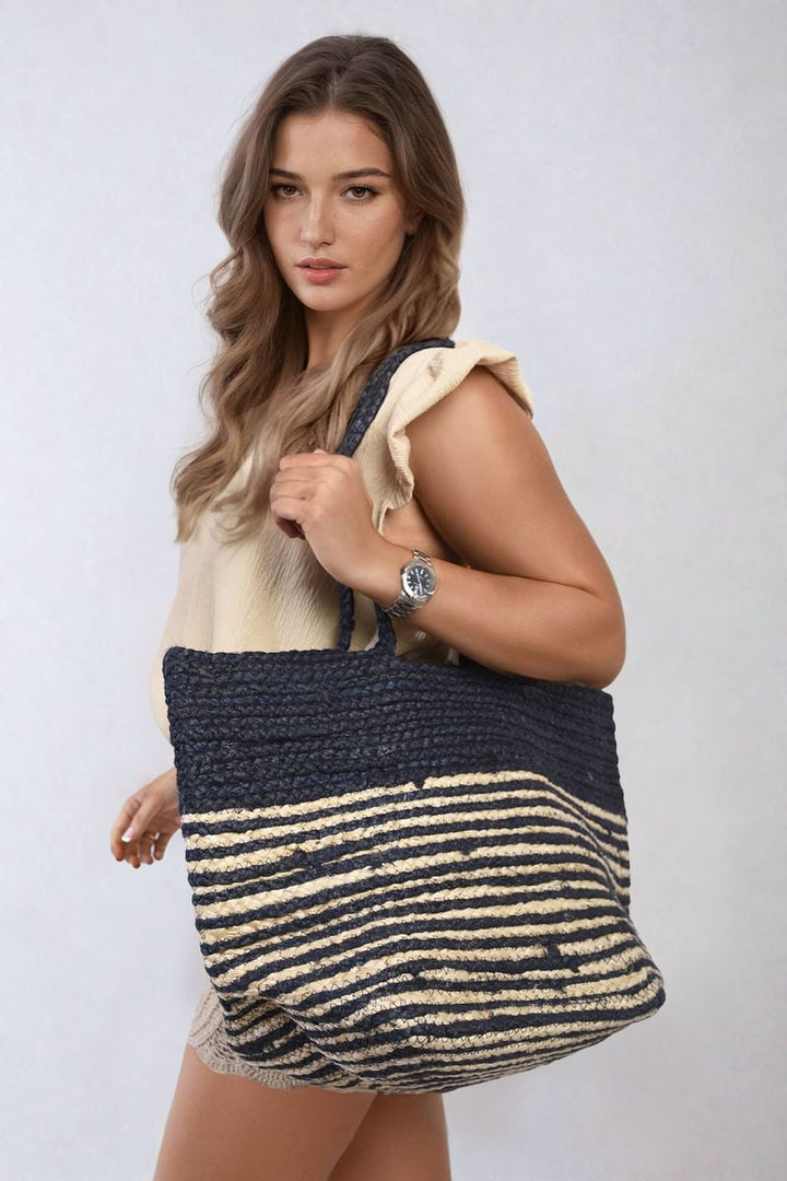 Woman holding the Striped Beach Braided Tote Bag with braided handles, showcasing its spacious design and stylish striped pattern.