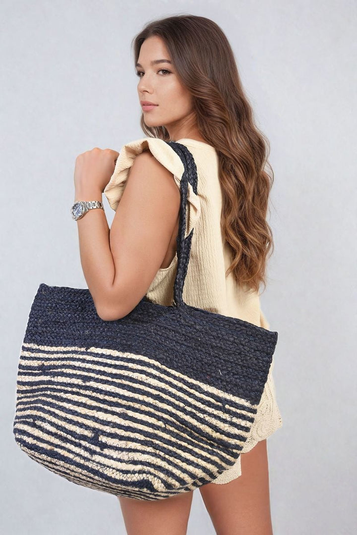 Woman holding a Louisa Striped Beach Braided Tote Bag, showcasing its chic striped design and braided handles, perfect for beach outings and everyday use.