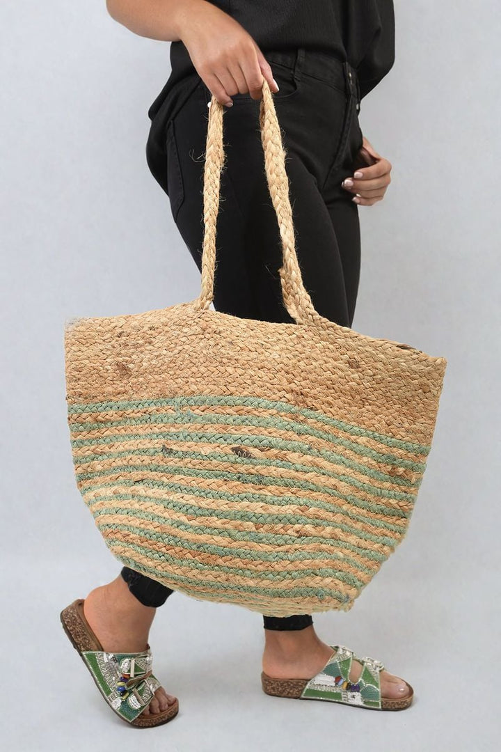 Woman holding Louisa Striped Beach Braided Tote Bag with braided handles, showcasing its chic striped design and spacious interior for versatile beach and everyday use.