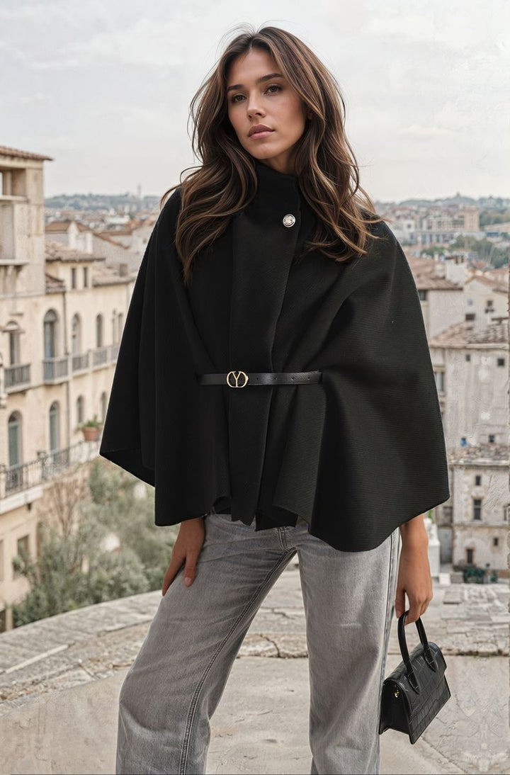 Woman standing on ledge wearing the Luciana High Neck Belted Cape Jacket, showcasing its elegant high neck and stylish belt design.