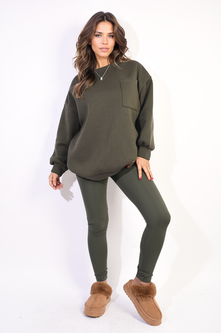 Woman in green oversized pocket sweatshirt and leggings, posing with brown slippers, showcasing the Lucy Co-ord Set for versatile comfort and style.