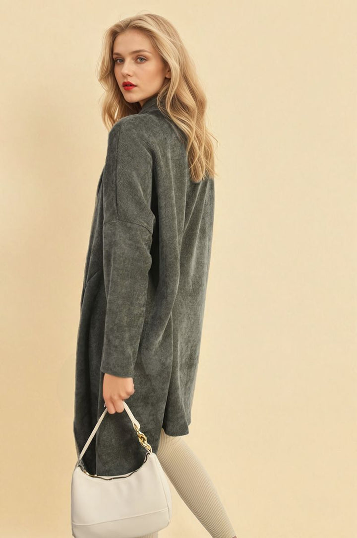 Woman in a grey Open Front Long Back Knitted Cardigan, holding a white purse, showcasing a stylish and cozy look perfect for casual or dressed-up occasions.