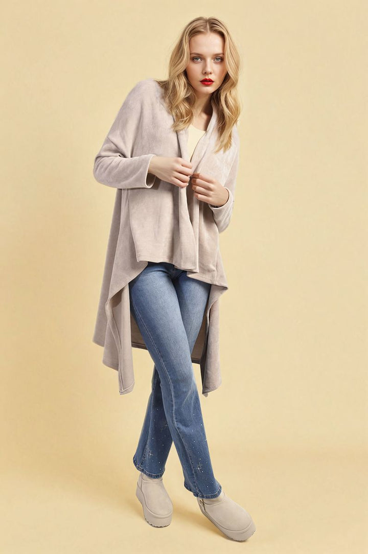 Woman in a beige Open Front Long Back Knitted Cardigan and blue jeans, showcasing the cardigan's flowy design and cozy knit from Holiday-clothes.co.uk.