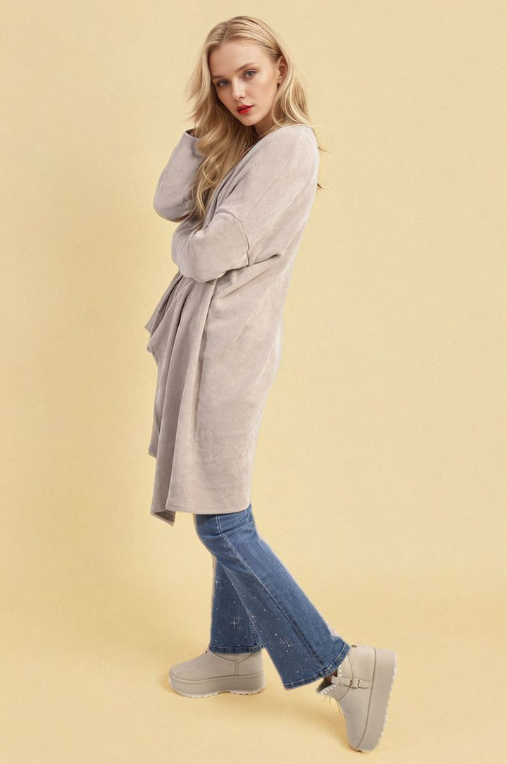 Woman wearing the Lydia Open Front Long Back Knitted Cardigan, showcasing its flowy design and cozy knit, paired with boots for a chic, casual look.