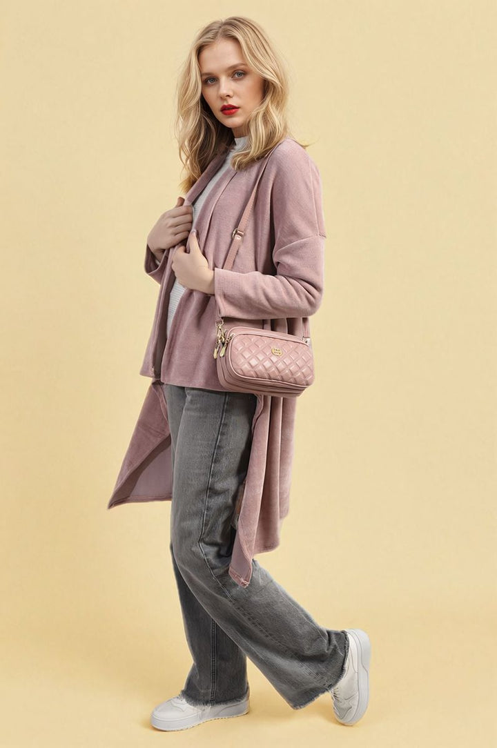 Woman wearing the Lydia Open Front Long Back Knitted Cardigan, styled casually with jeans and holding a pink purse, showcasing its cozy and flowy design.