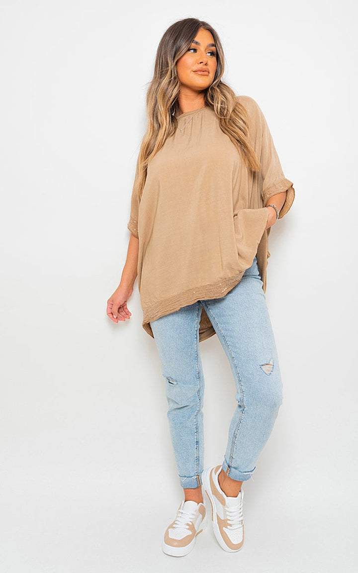 Woman wearing the Lydia Oversized Sequin Trim Top with blue jeans, showcasing its relaxed fit and dazzling sequin details, perfect for stylish occasions.