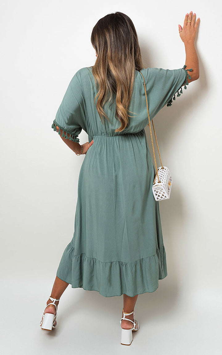 V-Neck Rope Tassel Detail Maxi Dress featuring a woman in a green dress holding a white purse with gold chains, showcasing elegant design and bohemian flair.