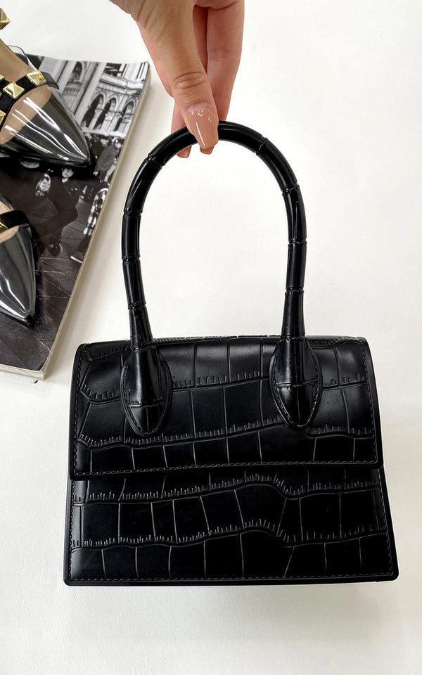 Hand holding a Maren Croc Print Handbag, showcasing its chic faux leather design and spacious interior for stylish outings.