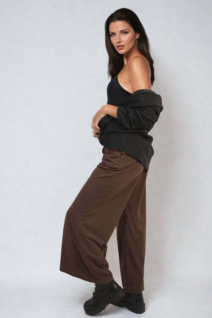 Woman wearing Belted High Waist Wide Leg Trouser, showcasing high-waisted fit and wide leg design, paired with black boots, embodying chic, versatile holiday style.