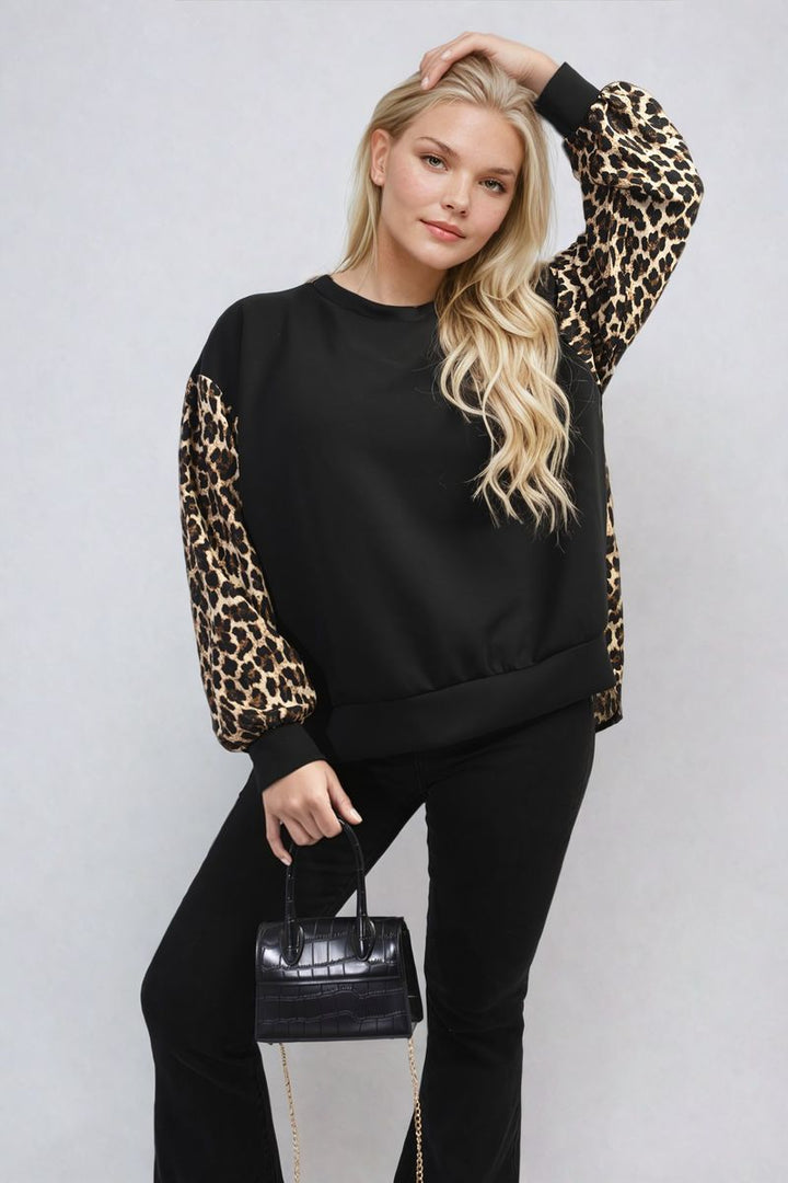 Woman wearing a Leopard Print Long Sleeve Knitted Jumper, holding a black purse with gold chains, showcasing cozy and trendy fashion.