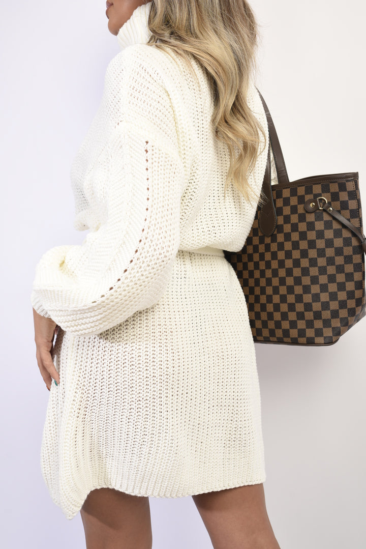 Woman wearing Long Sleeve Ribbed Knit Mini Dress With Belt, accessorized with a checkered purse, showcasing stylish holiday fashion from Holiday Clothes UK.