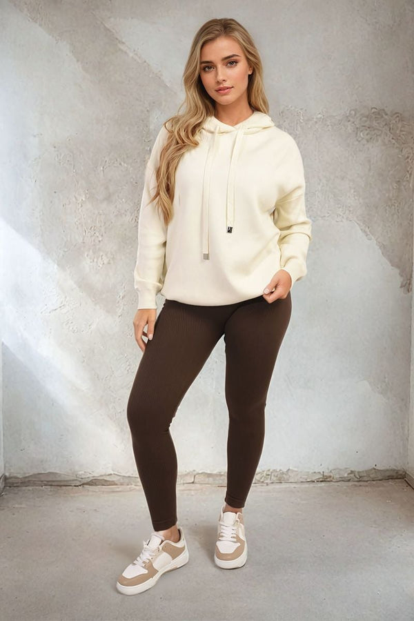 Woman wearing the Mikayla Back Heart Print Knitted Hoodie, showcasing a fun heart print on the back, paired with casual brown pants and stylish footwear.