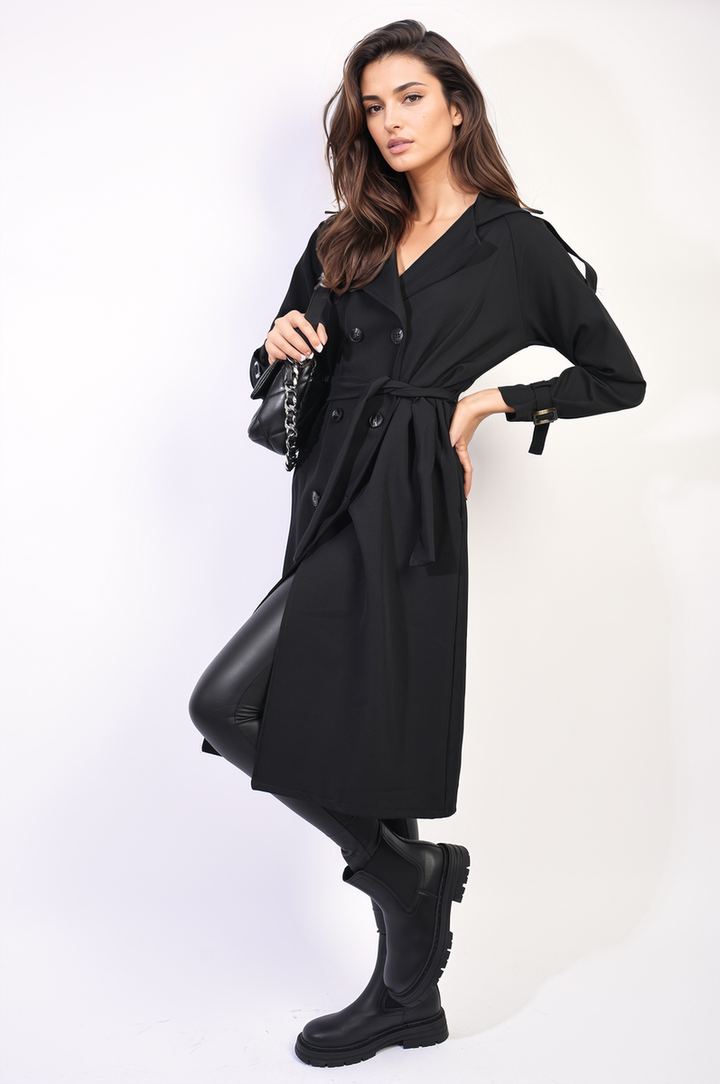 Woman modeling a Waist Tie Button Detailed Trench Coat, showcasing the chic waist tie and button details, paired with a black purse and boots.