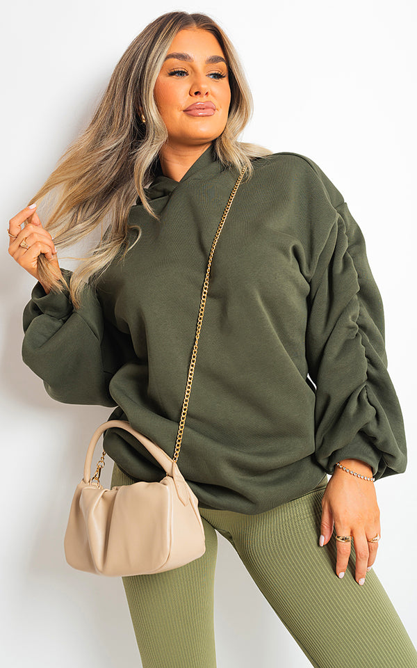 Woman in a Fall Winter Oversized Ruched Sleeves Hoodie, showcasing cozy and stylish design with a fashionable handbag accessory.