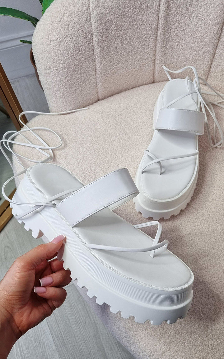 Faux Leather Strappy Lace Up Sandals with statement strap detail, held by a person, showcasing their stylish, durable faux leather construction for a glamorous look.