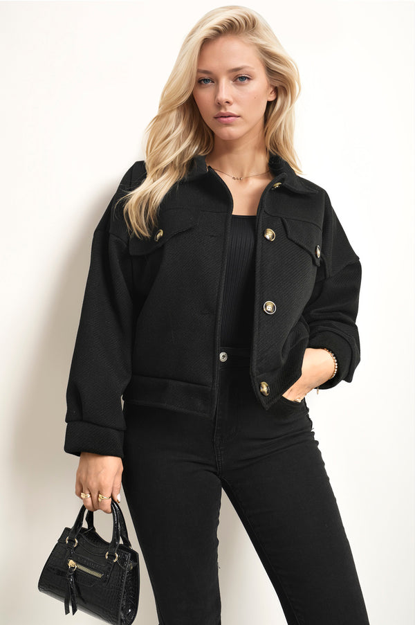 Woman wearing the Nadia Flap Pocket Long Sleeve Crop Jacket, holding a black purse, showcasing the jacket's cropped design and functional flap pockets.