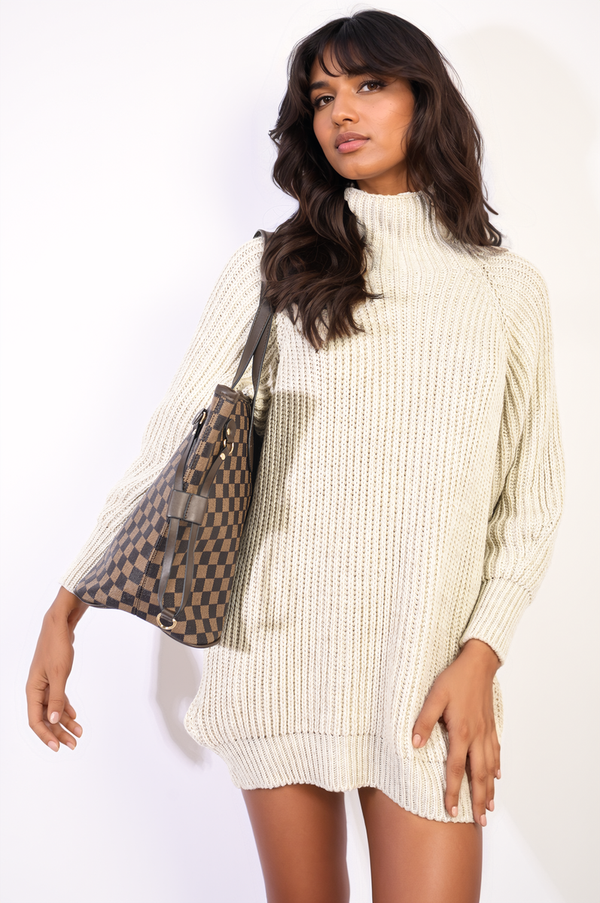 Woman in a white Knitted Turtleneck Mini Dress holding a handbag, showcasing a stylish look with black tights, perfect for a cozy, chic outfit.