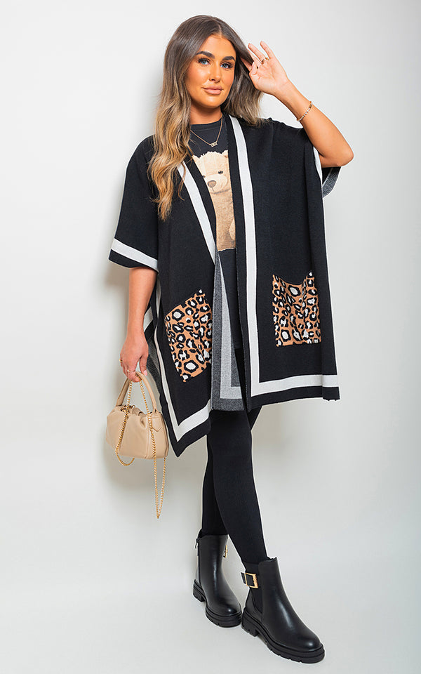 Woman modeling the Nadia Leopard Pocket Wrap Knitted Cardigan, featuring a leopard pattern and wrap design, paired with black boots and a tan purse.