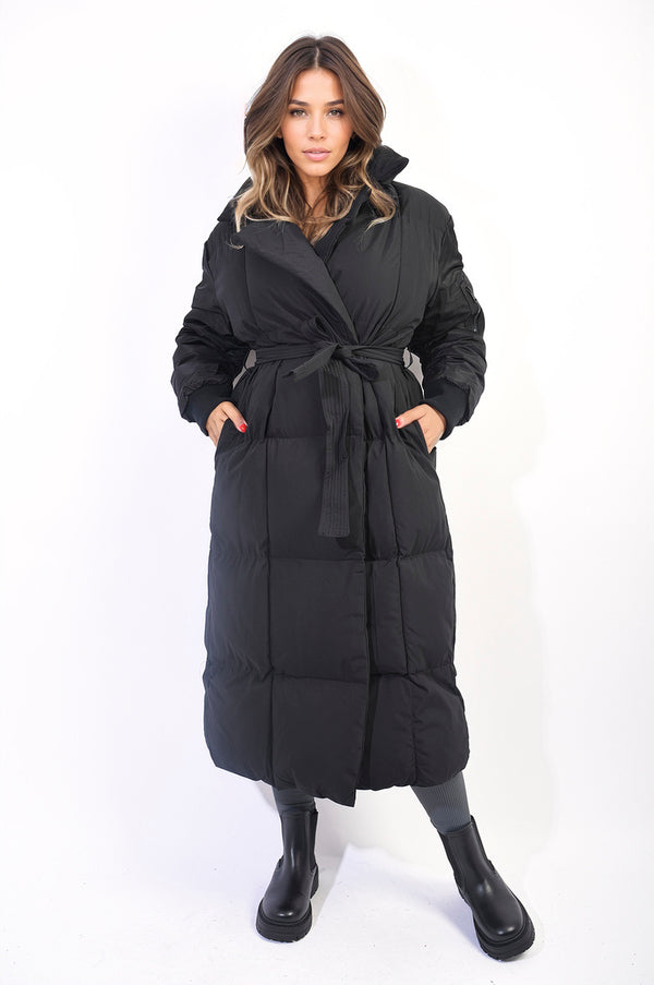 Woman wearing the Natasha Long Belted Puffer Coat, showcasing its longline, belted design for warmth and style. Ideal for winter fashion.