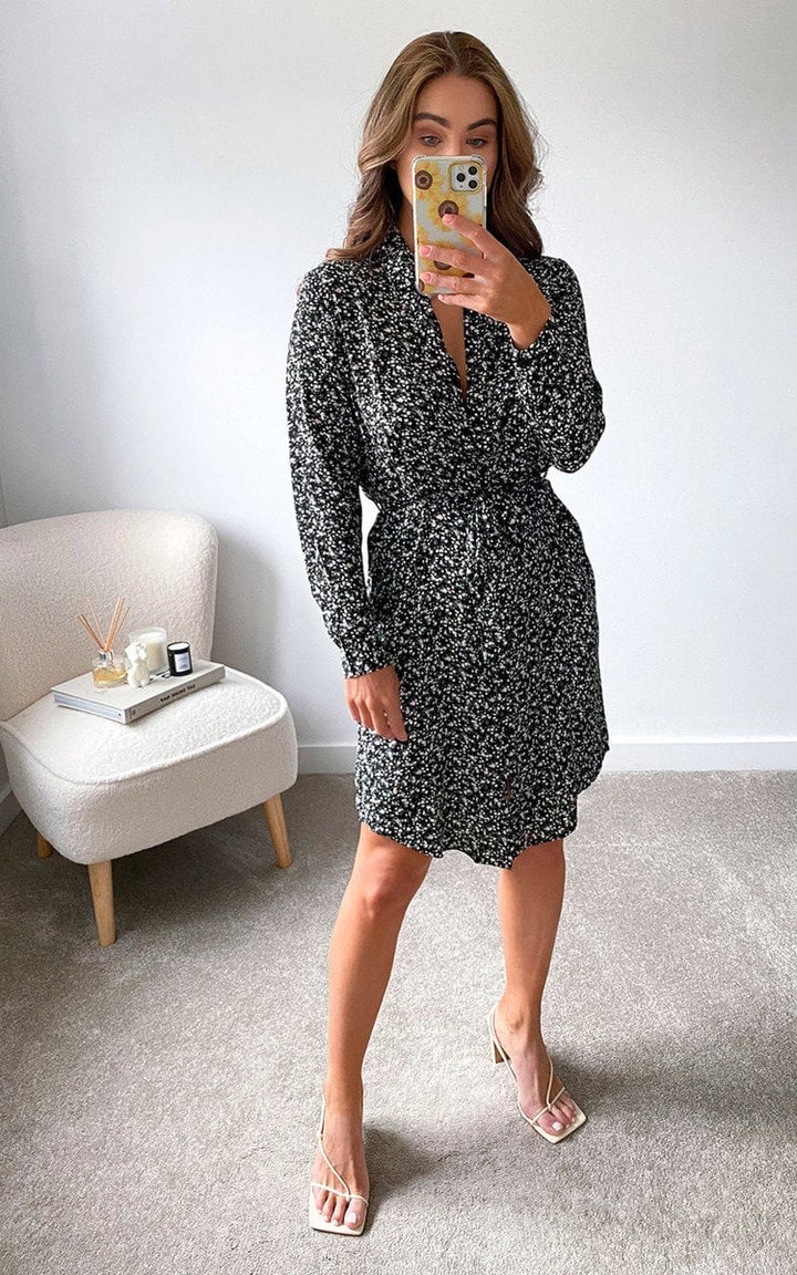 Woman in a Printed Mini Dress takes a selfie, showcasing the dress's loose fit and V-neck design, perfect for pairing with summer sandals.