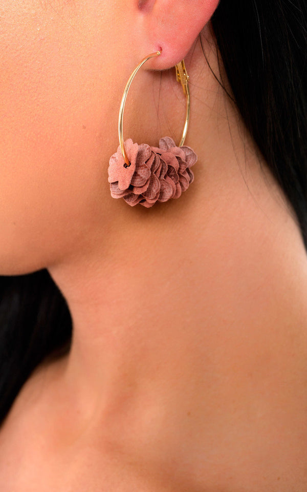 Close-up of a woman's ear wearing the Flower Hoop Earrings, showcasing gold-plated hoops with a floral design, perfect for pairing with chic holiday outfits.