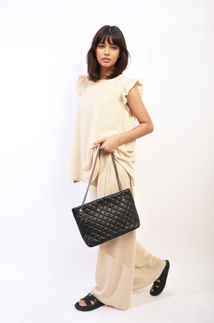 Woman wearing the Nova Ruffle Trim Top and Wide Leg Trouser Co-ord Set, holding a black purse, showcasing sophisticated and modern style.