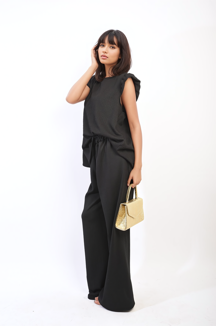 Woman in black outfit showcasing the Nova Ruffle Trim Top and Wide Leg Trouser Co-ord Set, highlighting its elegant ruffle details and modern, chic style.