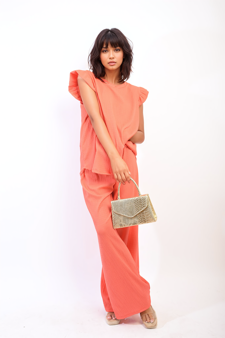 Ruffle Trim Top and Wide Leg Trouser Co-ord Set worn by a woman holding a gold purse, showcasing elegant and contemporary fashion.