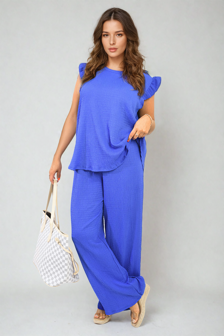 Woman wearing Ruffle Trim Top and Wide Leg Trouser Co-ord Set, holding a bag, showcasing effortless elegance and contemporary chic from Holiday Clothes UK.