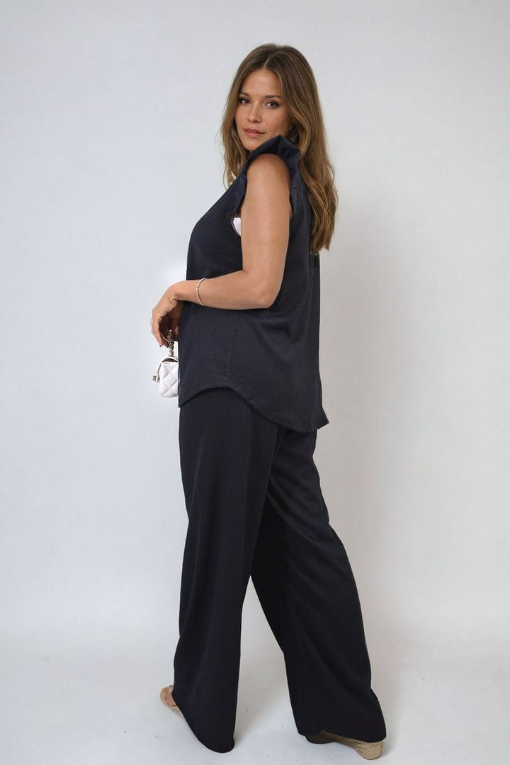 Woman modeling the Ruffle Trim Top and Wide Leg Trouser Co-ord Set, showcasing its chic design and elegant fit. Perfect for stylish, versatile holiday wear.