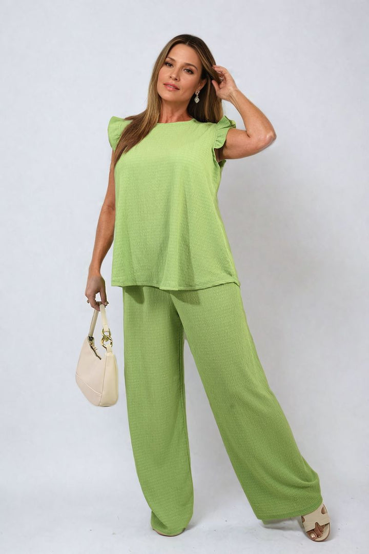 Woman wearing the Nova Ruffle Trim Top and Wide Leg Trouser Co-ord Set, showcasing its ruffle detail and high-waisted trousers for an elegant look.