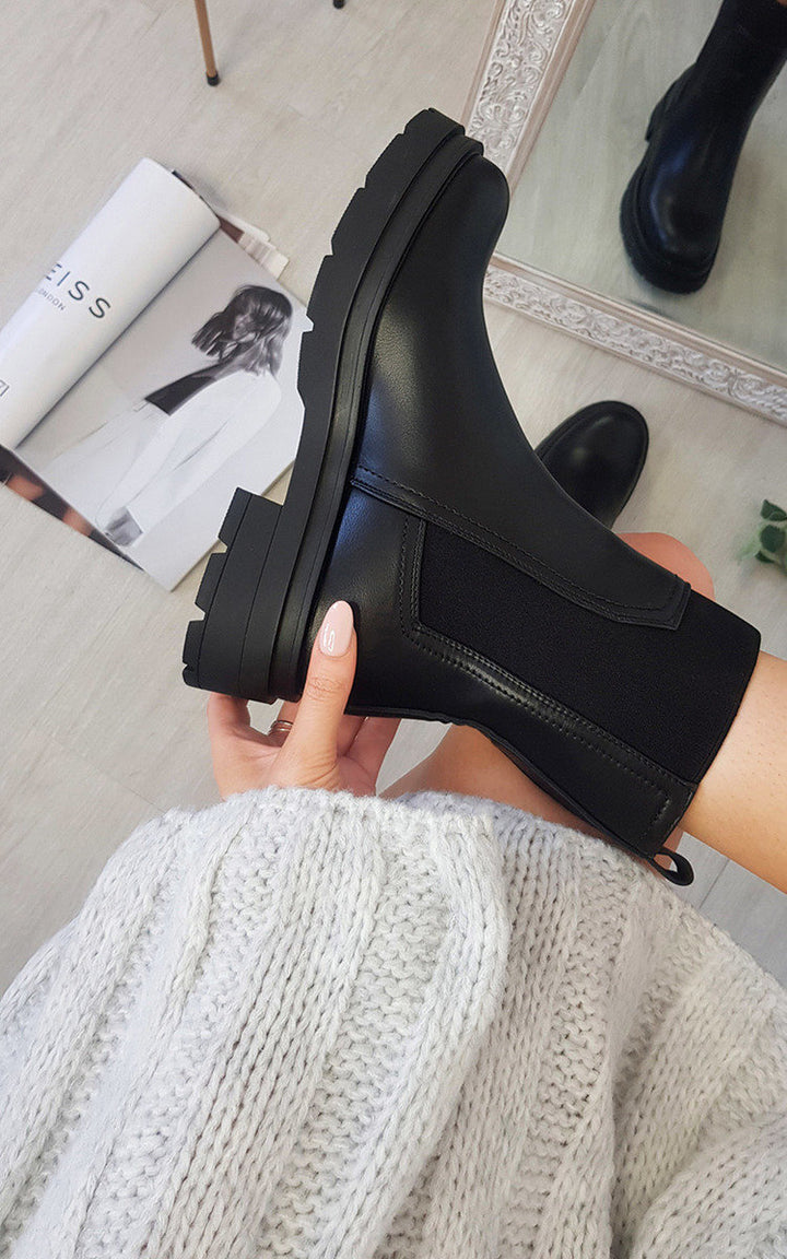 Person holding Chunky Ankle Boots, ideal for versatile styling with slacks, dresses, and skirts. Perfect for keeping feet warm this winter.