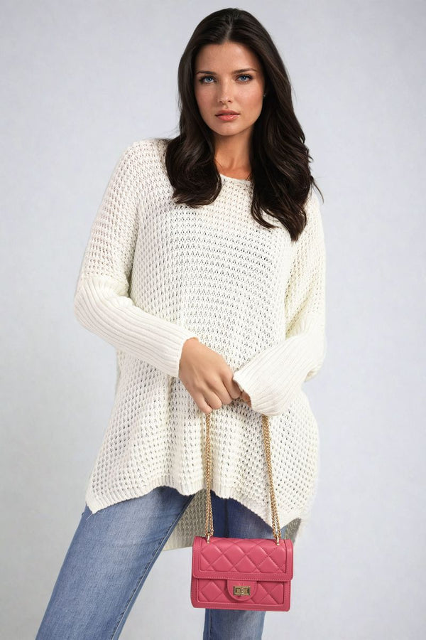 Woman in a white sweater carrying a pink handbag with gold chains, showcasing the stylish Long Back Knitted Long Sleeve Jumper for casual outings.