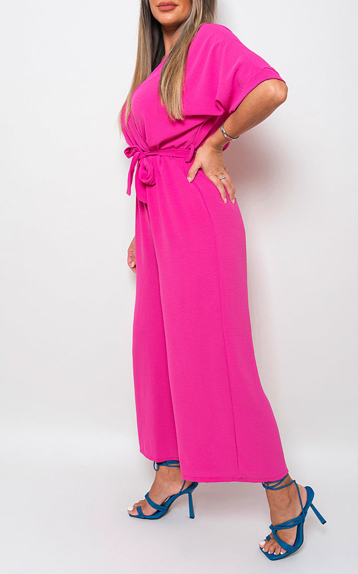 Woman wearing V Neck Tie Waist Short Sleeve Jumpsuit, featuring a chic v-neckline and flattering tie waist, perfect for versatile summer styling.