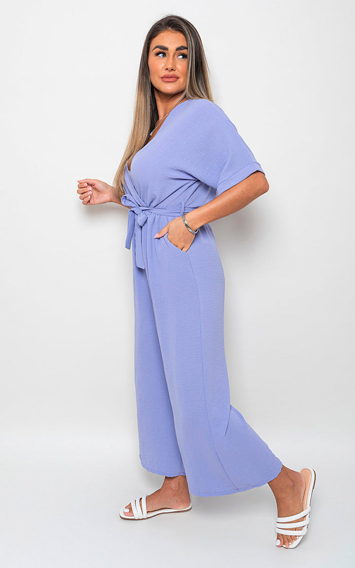 Woman wearing a V Neck Tie Waist Short Sleeve Jumpsuit, showcasing its stylish design with a flattering silhouette and chic v-neckline.