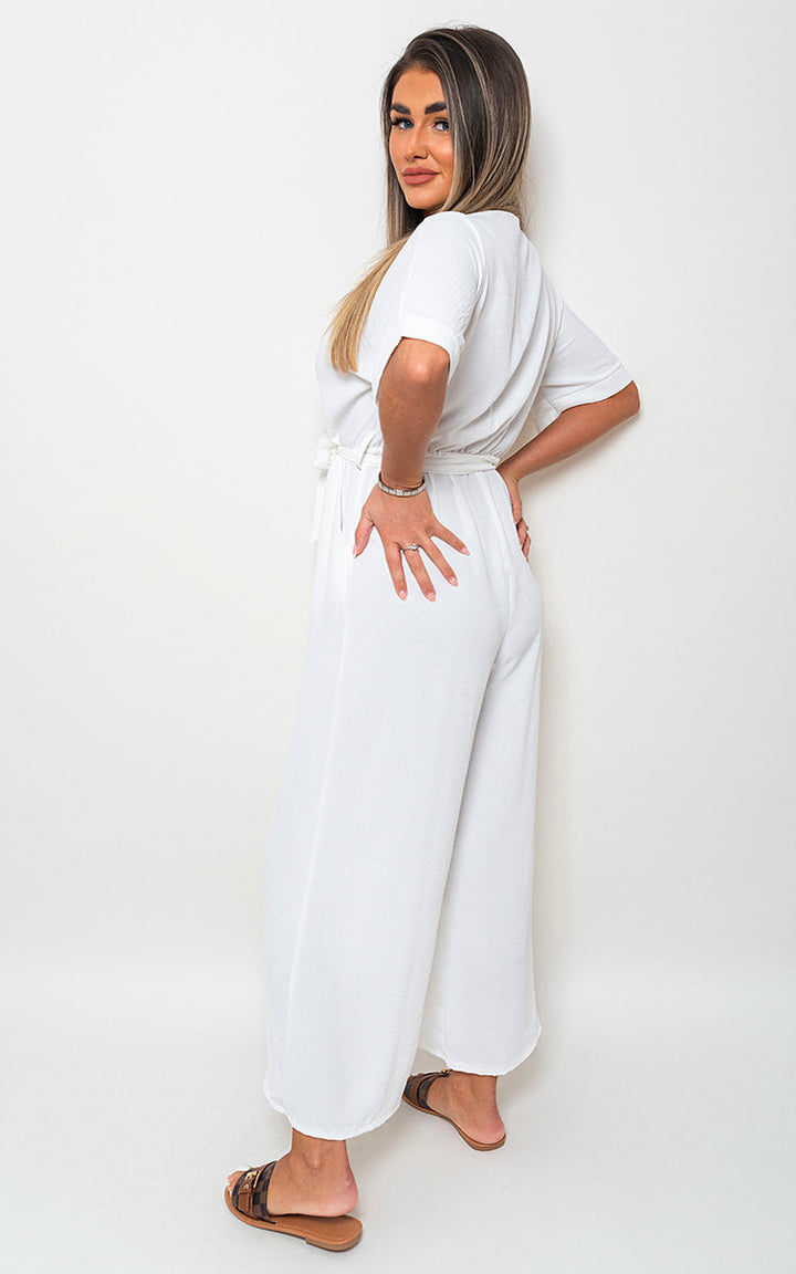 Woman wearing V Neck Tie Waist Short Sleeve Jumpsuit, showcasing its chic v-neckline and flattering tie waist, perfect for versatile summer fashion from Holiday Clothes UK.