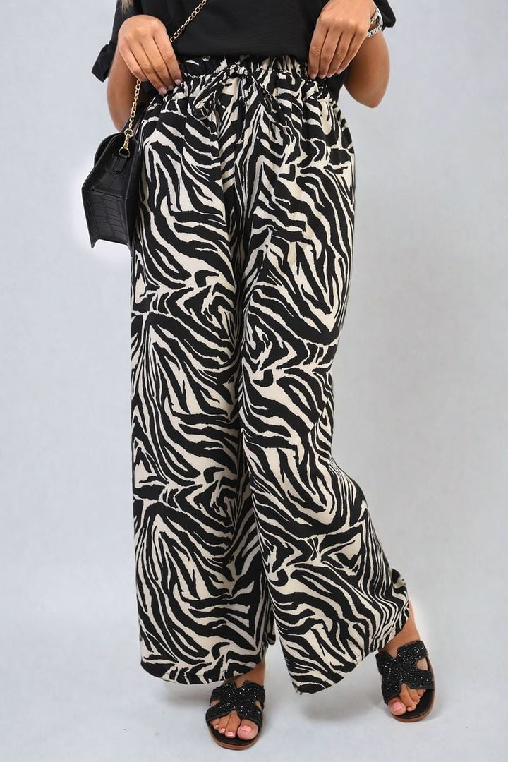 Zebra-Striped Print Wide Leg Trousers worn by a woman, paired with a black purse, showcasing a high-waist design and bold animal print.