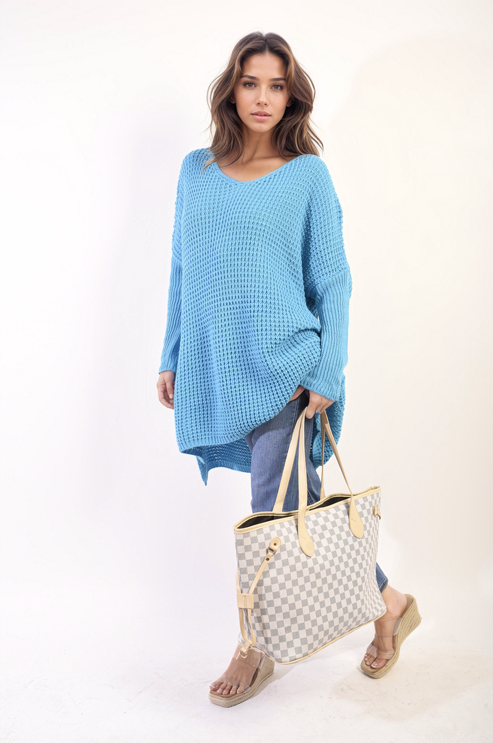 Woman wearing an oversized chunky knitted jumper while holding a checkered bag, showcasing the cozy Rebecca jumper from Holiday-clothes.co.uk.