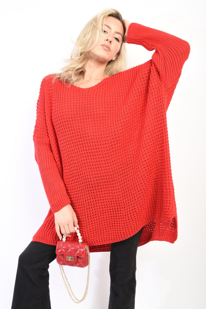 Woman in an oversized chunky knitted jumper holding a red purse, showcasing cozy winter style from Holiday Clothes UK.