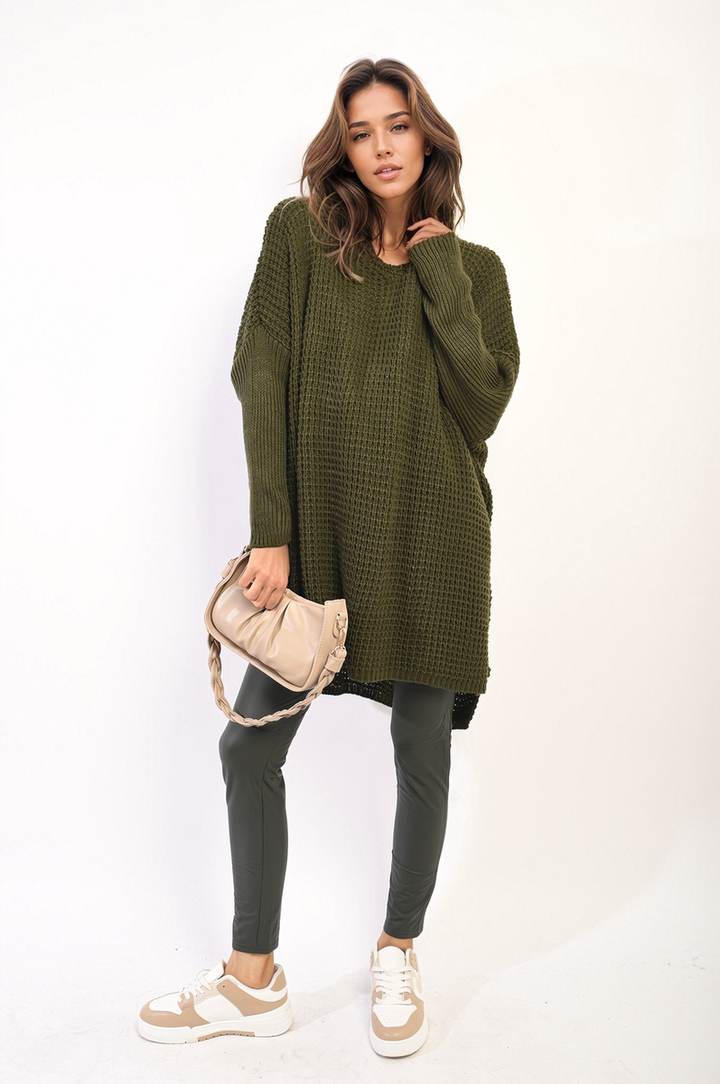 Woman wearing Rebecca Oversized Chunky Knitted Jumper, holding a purse, styled with casual white sneakers, showcasing cozy, relaxed fashion.