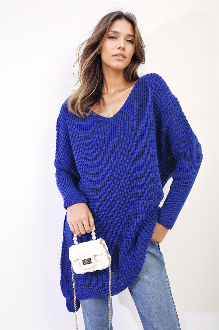 Woman in blue sweater, holding a white purse. Showcasing the Rebecca Oversized Chunky Knitted Jumper, a cozy and stylish essential for chilly days.