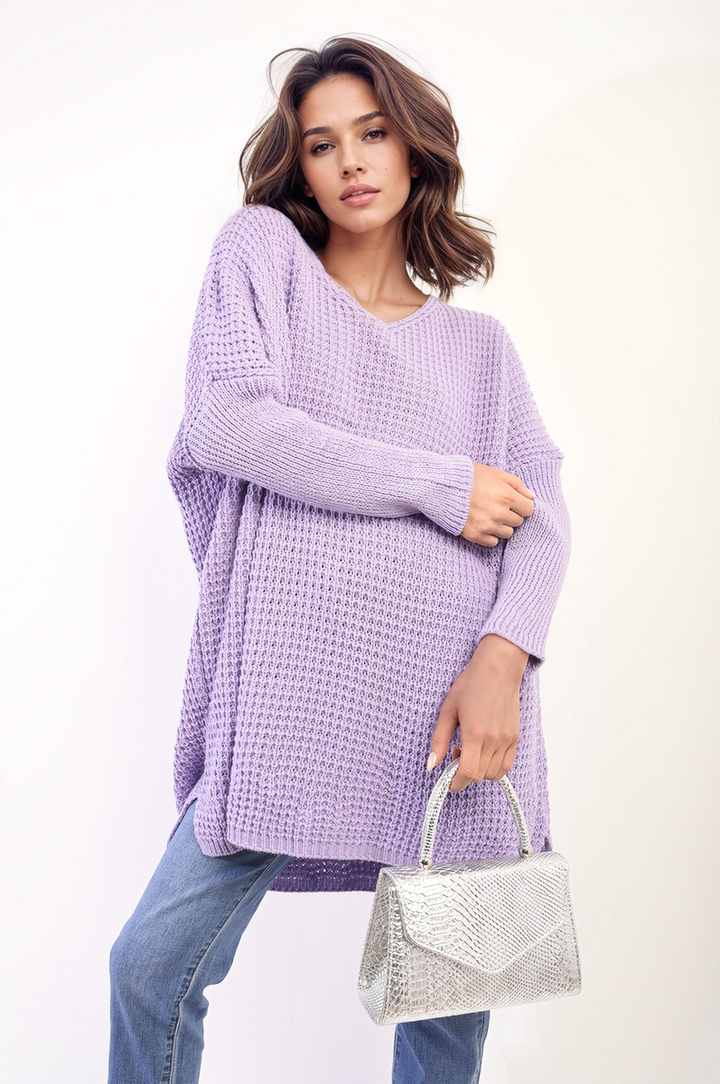 Woman in oversized chunky knitted jumper holding a silver purse, showcasing the cozy Rebecca Jumper from Holiday Clothes UK's collection.