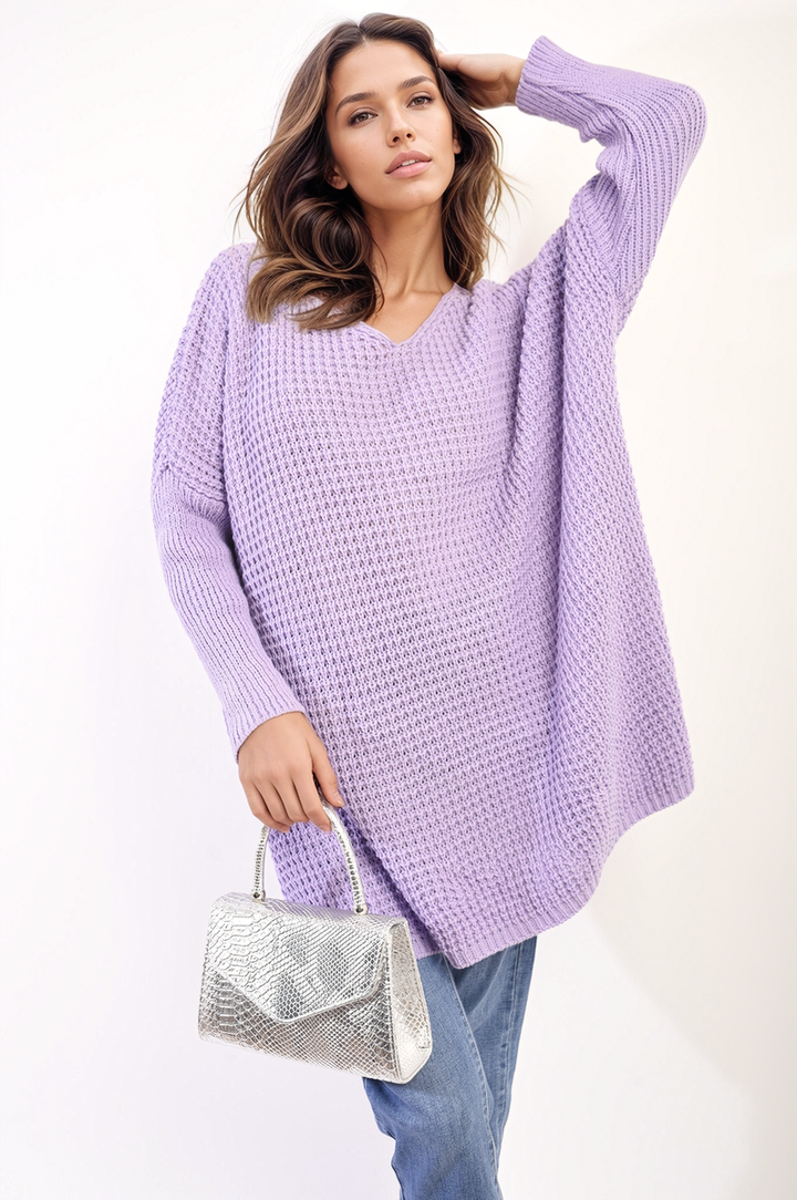 Woman in a purple sweater holds the Oversized Chunky Knitted Jumper, showcasing its cozy, relaxed fit and stylish design from Holiday Clothes UK.