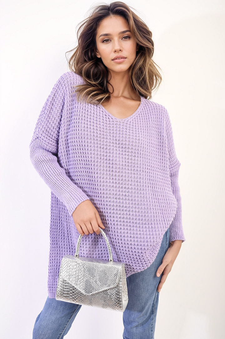 Woman holding a silver purse, wearing the Rebecca Oversized Chunky Knitted Jumper, showcasing its cozy, relaxed fit perfect for casual outings.