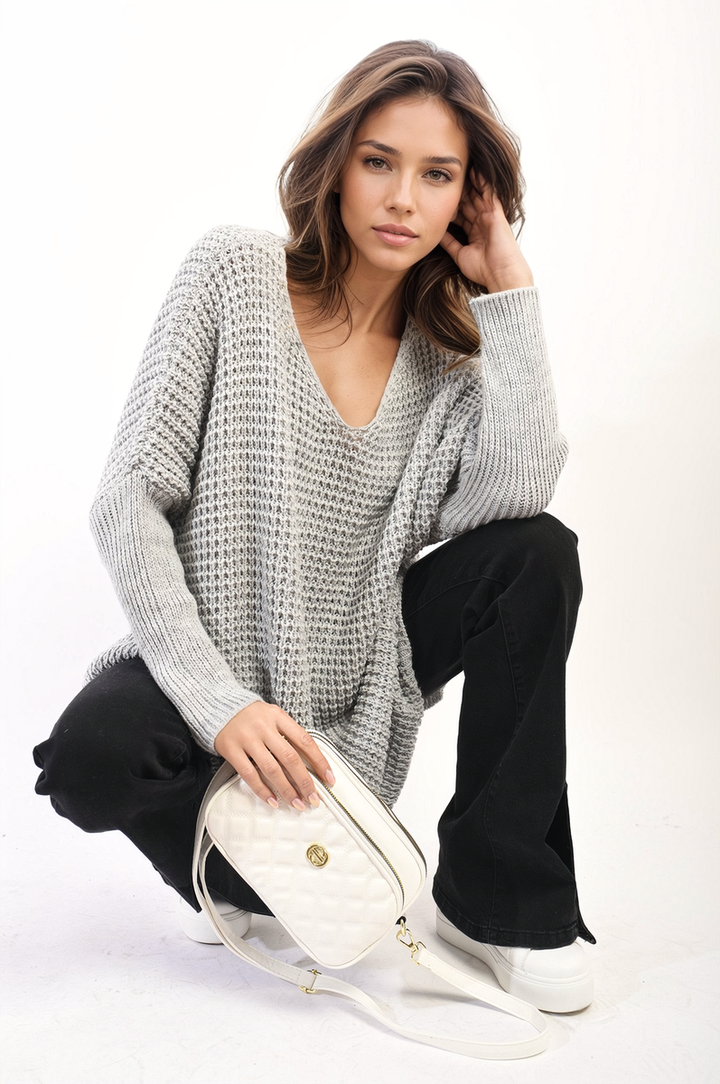 Woman wearing the Rebecca Oversized Chunky Knitted Jumper, sitting with a white purse, showcasing the jumper's cozy, relaxed fit suitable for casual outings.