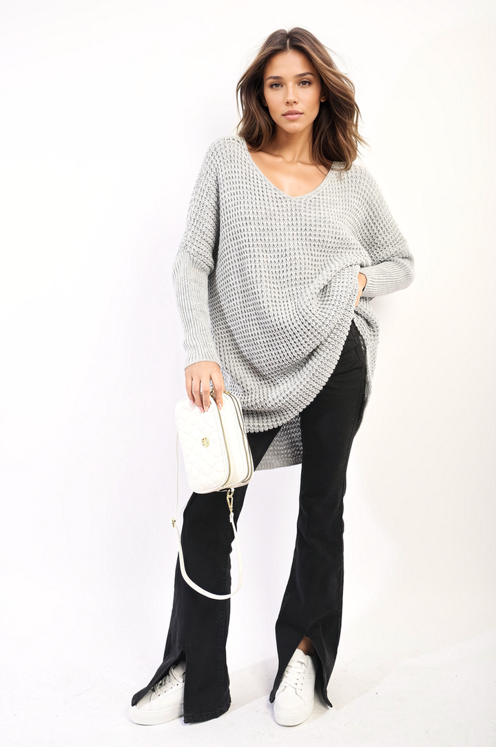 Woman wearing oversized chunky knitted jumper, holding a purse, showcasing the cozy Rebecca jumper, ideal for casual outings and chilly days.