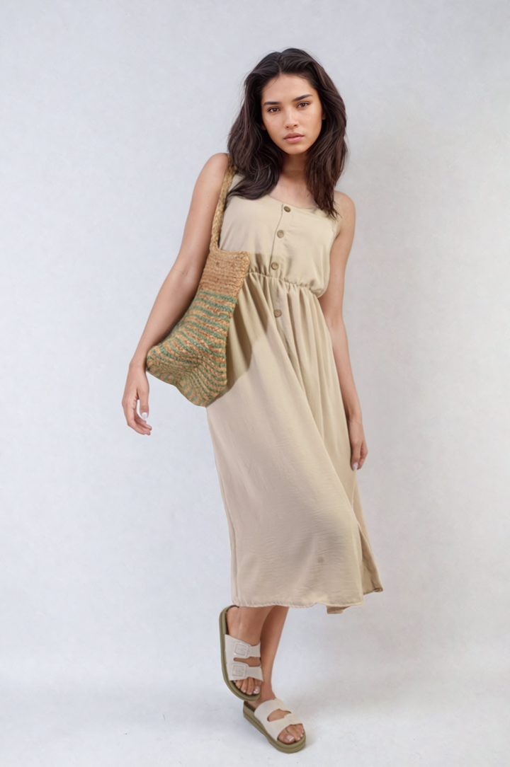 Woman wearing the Button Front Strappy Midi Dress, holding a knitted purse, showcasing the dress's elegant button detail and strappy design for stylish summer outings.